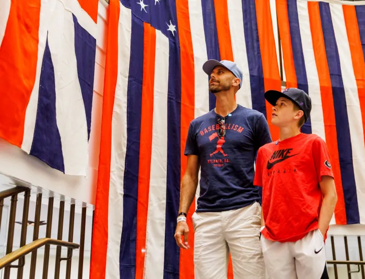 Man and teenage boy look at red, white, and blue flags
