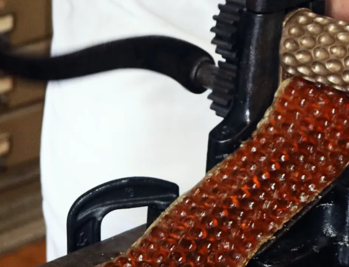 hard candy being produced by an antique hand cranked machine