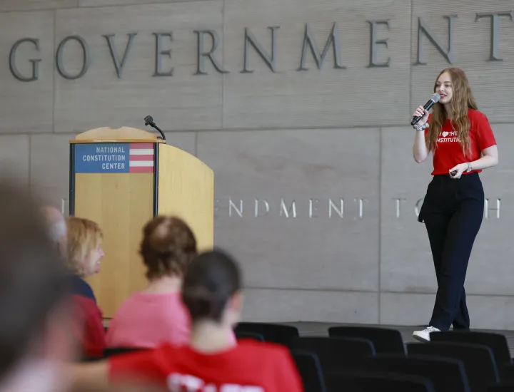 Woman presenting a program on a stage in a museum.
