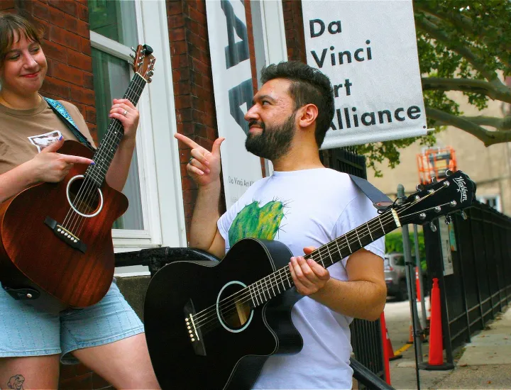 Two musicians smiling with their guitars posing outside of DVAA.