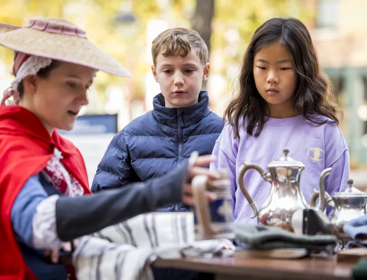 Woman pouring tea for two children looking on