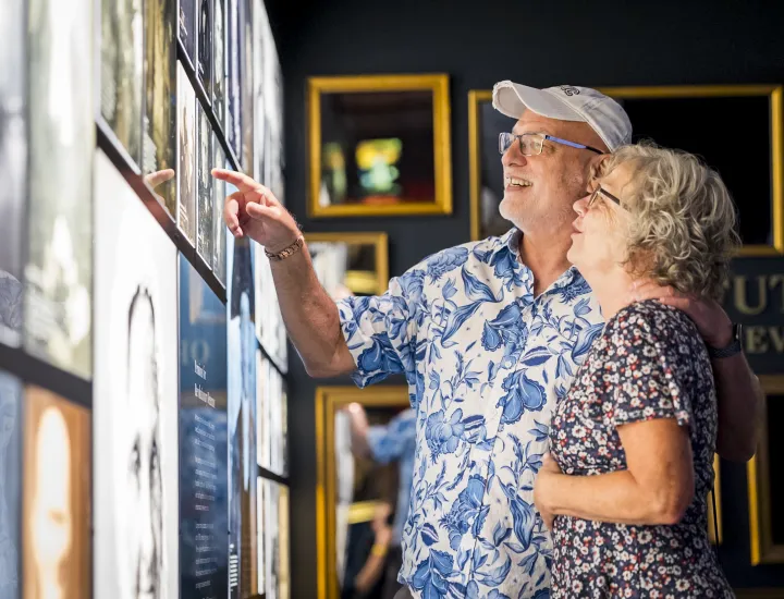 A man and woman view wall of photos of 19th-century portraits