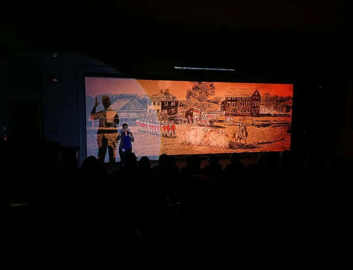 ASL interpreter stands in left corner signing during film screening