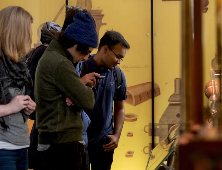 Group of three people looking down at a display in the Science History Institute's museum. 
