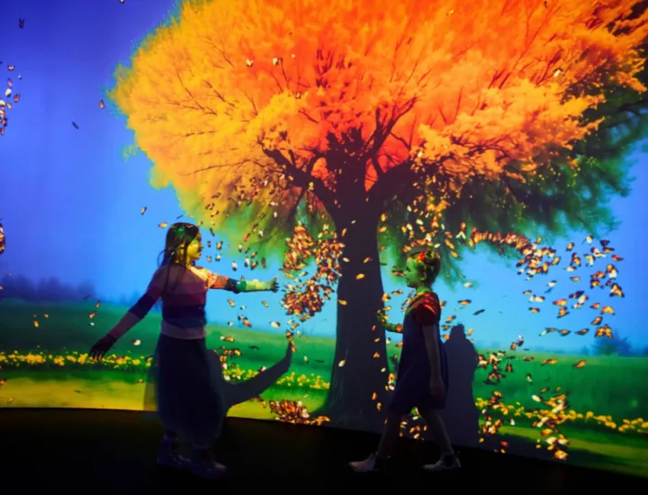 two girls standing in front of a tree with images of butterflies around them